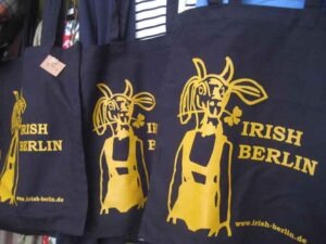 Schwarze Stofftaschen mit gelbem Schafmotiv und Schriftzug „Irish Berlin“ auf einem Verkaufsstand