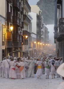 Karneval auf La Palma 2026: Wenn die Insel Geschichte feiert 23 Menschen in weißen Kostümen ziehen durch eine schmale Straße mit historischen Balkonen und Pudernebel.