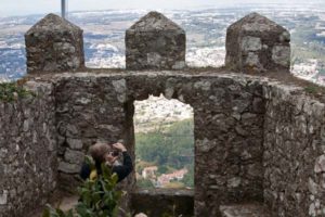 Steinmauer des Castelo dos Mouros mit Ausblick auf Sintra und einen fotografierenden Besucher.