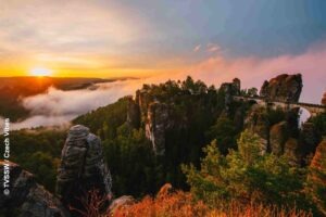 Malerweg Elbsandsteingebirge: Die Sächsische Schweiz auf Wagners Spuren bewandern 90 Basteibrücke zwischen Sandsteinfelsen im Licht des Sonnenaufgangs. Nebel zieht über das bewaldete Tal in der Sächsischen Schweiz.