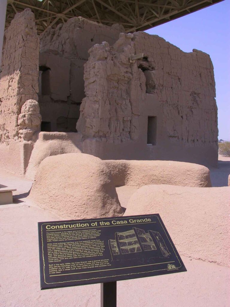 Spektakuläre Bauwerke der Ureinwohner in Arizona 7 Nahaufnahme der Lehmwände von Casa Grande im Casa Grande Ruins National Monument mit Infotafel zur Bauweise und dem darüberliegenden Schutzdach.