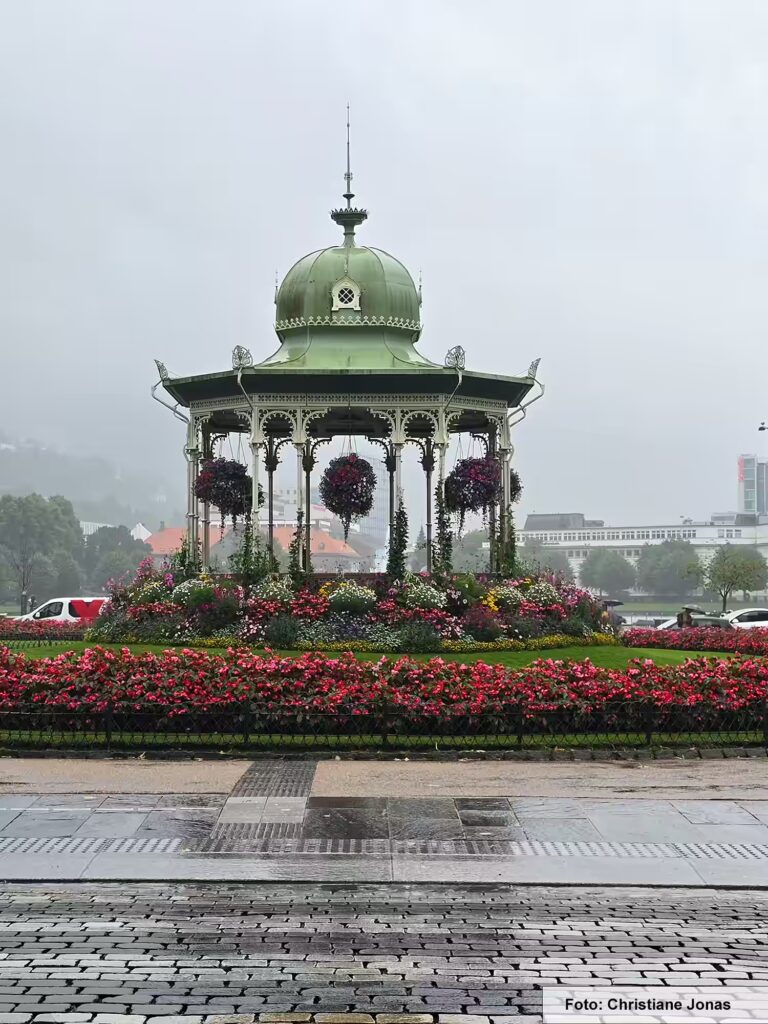 Das kannst du in Bergen ansehen – unsere Tipps 6 Der Musikpavillon von Bergen mit roten Blumen bei Regen