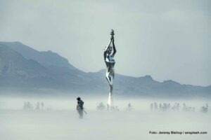 Die Kraft der Liebe - Festival Burning Man in der Wüste Nevadas 12 Eine Gruppe von Menschen steht auf einer nebelbedeckten Ebene. Mittendrin eine silbrige Statue von Lady Liberty