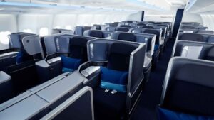Business-Class-Kabine von Discover Airlines im „Ocean Blue“-Design mit versetzt angeordneten Lie-Flat-Sitzen, hohen Trennwänden und blauen Kissen.