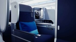 Nahaufnahme eines Discover-Airlines-Business-Class-Sitzes mit breiter Armlehne, Stauraum und blauen Kissen im „Ocean Blue“-Farbschema.