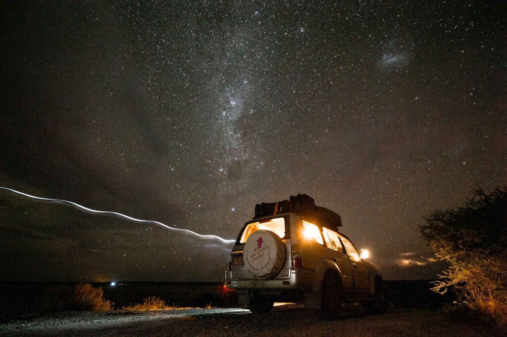 Wildnis erleben, Freiheit spüren - mit Miss Guided Safaris 4 Geländewagen von Miss Guided Safaris bei Nacht, beleuchtet unter einem klaren afrikanischen Sternenhimmel in der Wildnis.