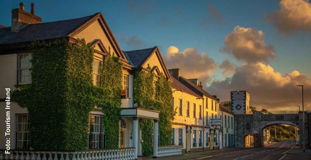Mit Efeu bewachsene Fassade des Harbourview Hotels in Carnlough, daneben die historische Straßenbrücke im warmen Abendlicht