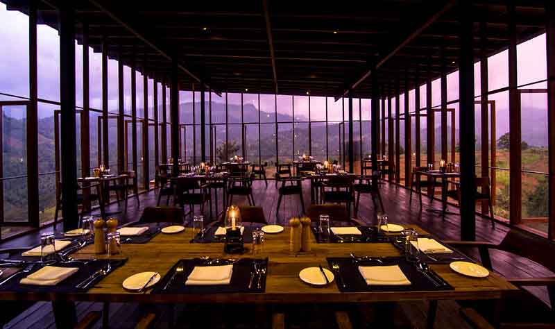 Santani Wellness Kandy: Luxus, Achtsamkeit und Natur im Einklang 3 Stilvoll gedeckter Tisch im gläsernen Restaurant des Santani Wellness Kandy bei Sonnenuntergang mit Bergblick.