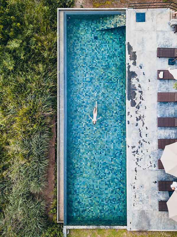 Santani Wellness Kandy: Luxus, Achtsamkeit und Natur im Einklang 8 Vogelperspektive auf rechteckigen Infinity-Pool mit einer schwimmenden Person, umgeben von Natur.