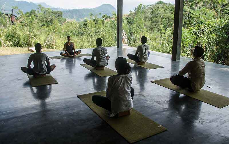 Santani Wellness Kandy: Luxus, Achtsamkeit und Natur im Einklang 6 Gruppe beim Yogaunterricht im überdachten Außenbereich des Santani Resorts mit Blick auf das grüne Umland.
