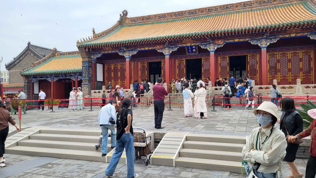 Kaiserpalast von Shenyang – Die „Verbotene Stadt“ des Nordens erleben 11 Große Palasthalle mit gelb-grünem Dach und roten Säulen im Shenyang-Kaiserpalast; zahlreiche Besucher im Vorfeld.