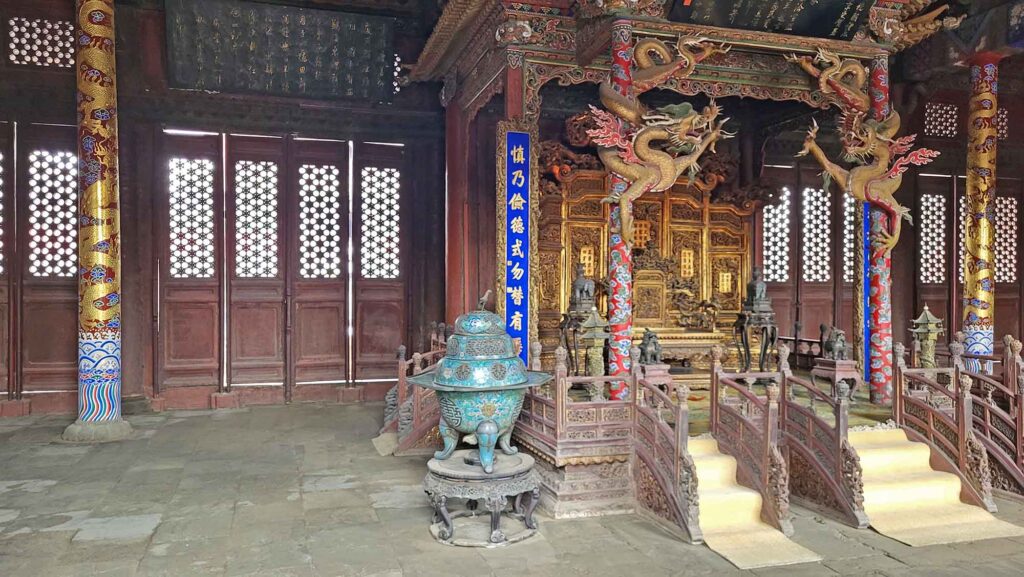 Kaiserpalast von Shenyang – Die „Verbotene Stadt“ des Nordens erleben 14 Innenraum mit erhöhtem Thron, roten Säulen mit goldenen Drachen und großem Räuchergefäß im Kaiserpalast Shenyang.