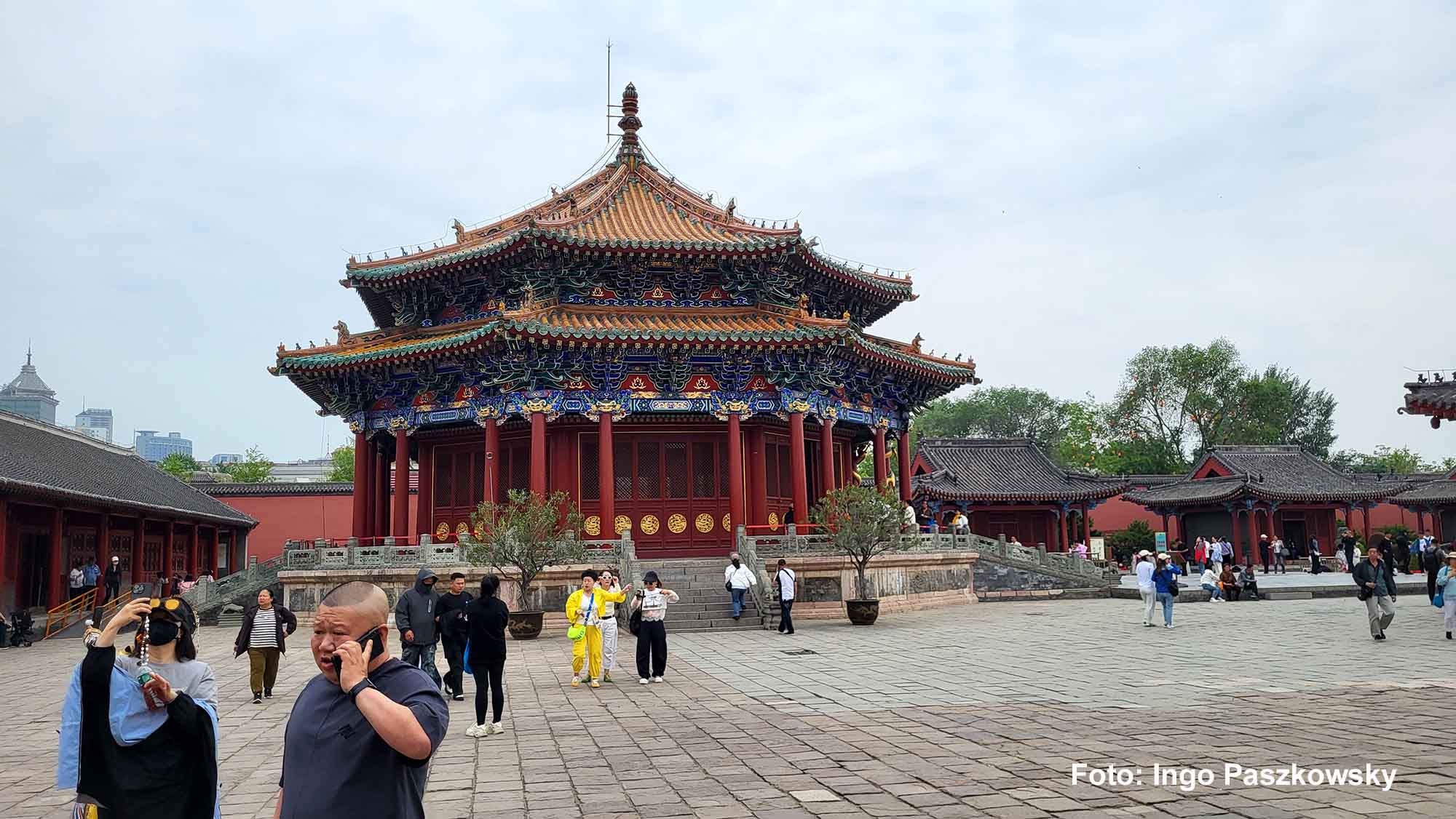Chongzheng-Palast: Großes, mehrstöckiges Gebäude mit einem reich verzierten Dach, roten Säulen und farbenfrohen Holzarbeiten, umgeben von einem großen gepflasterten Platz.