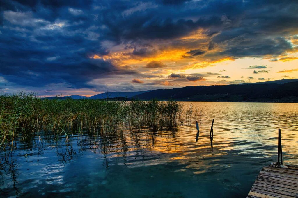 Durch eiskaltes Wasser und Stromschnellen schwimmen 8 Sonnenuntergang am Bielersee mit Schilf im Vordergrund und farbenprächtigem Himmel