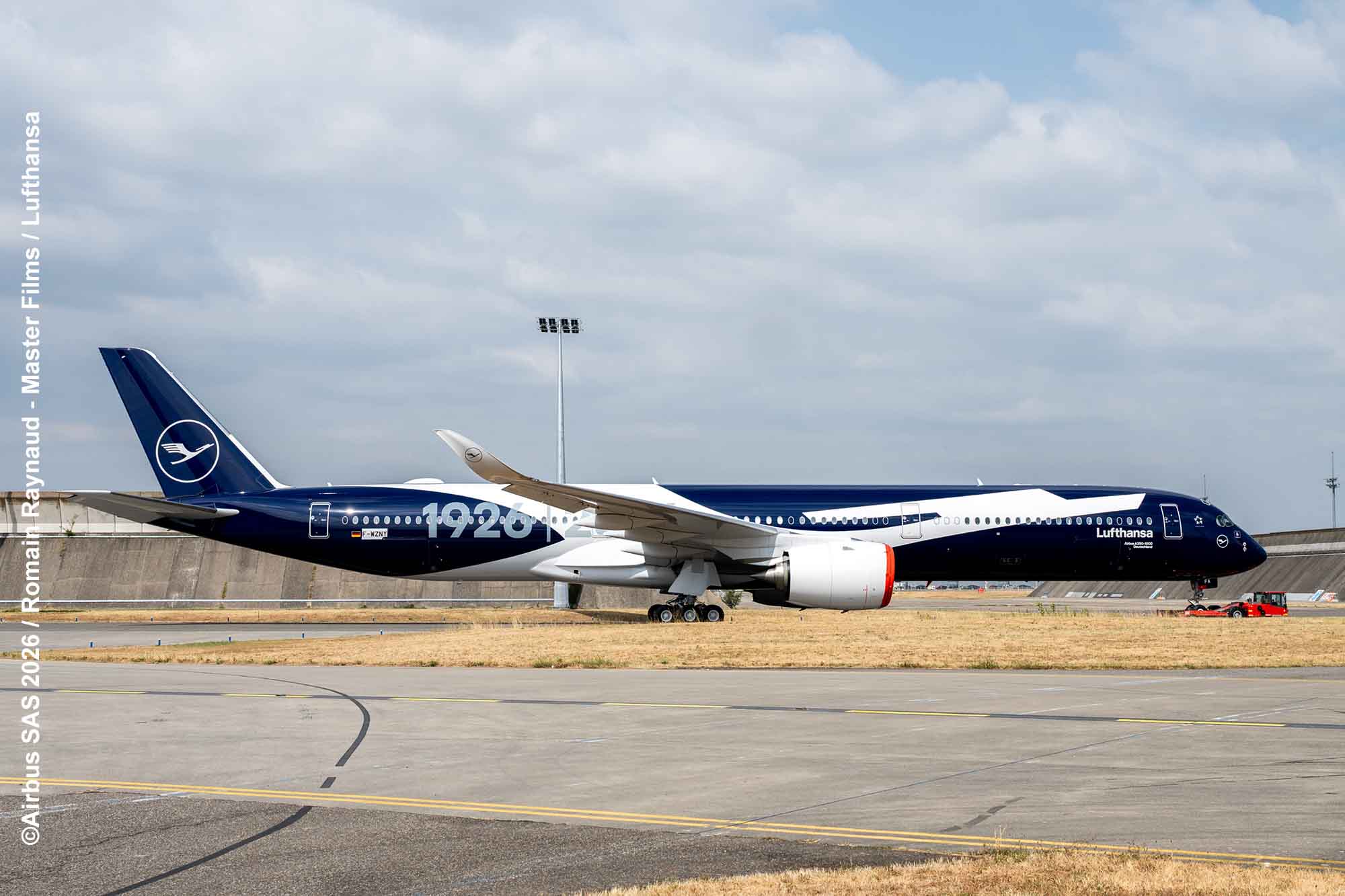 Lufthansa Airbus A350-1000 in dunkelblauer Jubiläumslackierung mit großer „100“-Aufschrift auf dem Flughafengelände.