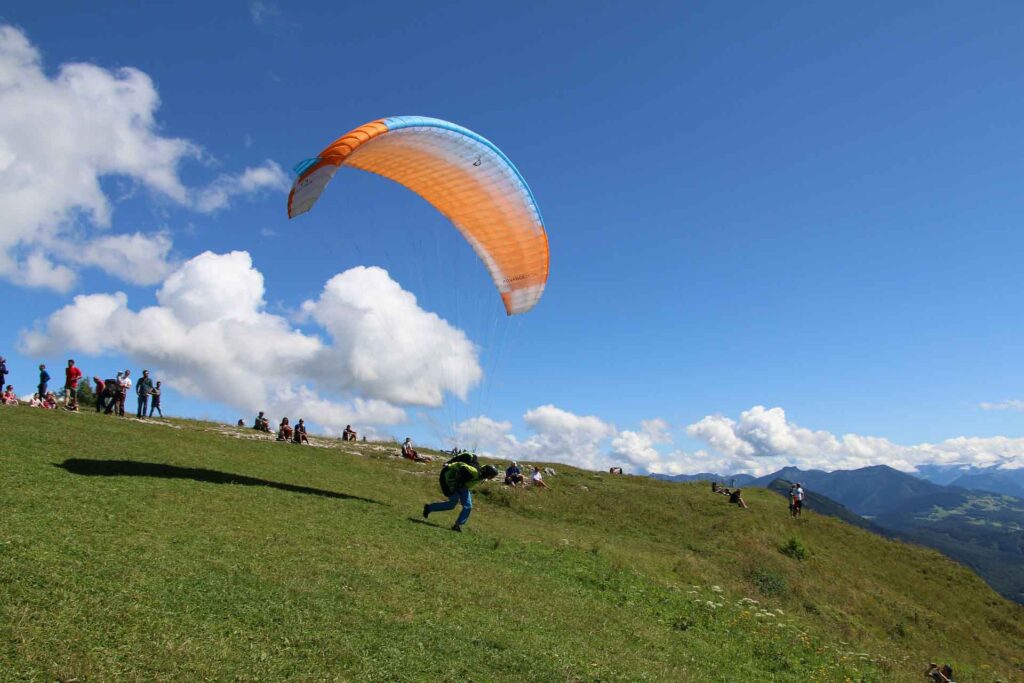 Alpenabenteuer: Fliegen über Salzburg und den Zeller See 4 Fliegen über Salzburg. Gleitschirmflieger läuft mit aufgespanntem Schirm zum Abheben den Berg hinunter