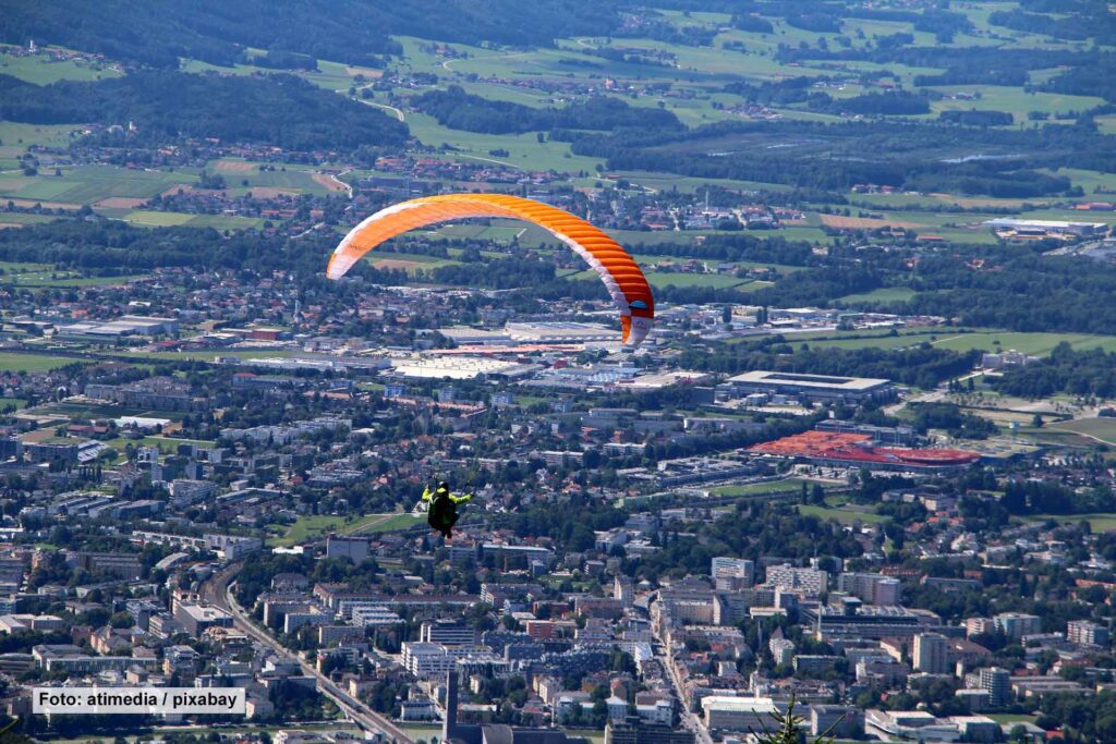 Person fliegt mit Gleitschirm über Salzburg