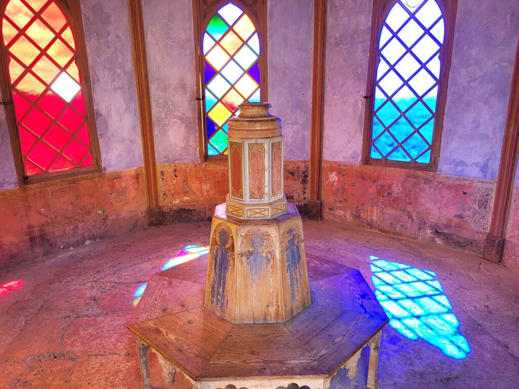 Historischer Pavillon mit bunten Glasfenstern im Landgut Raixa auf Mallorca, durch die farbiges Licht auf den Boden fällt.