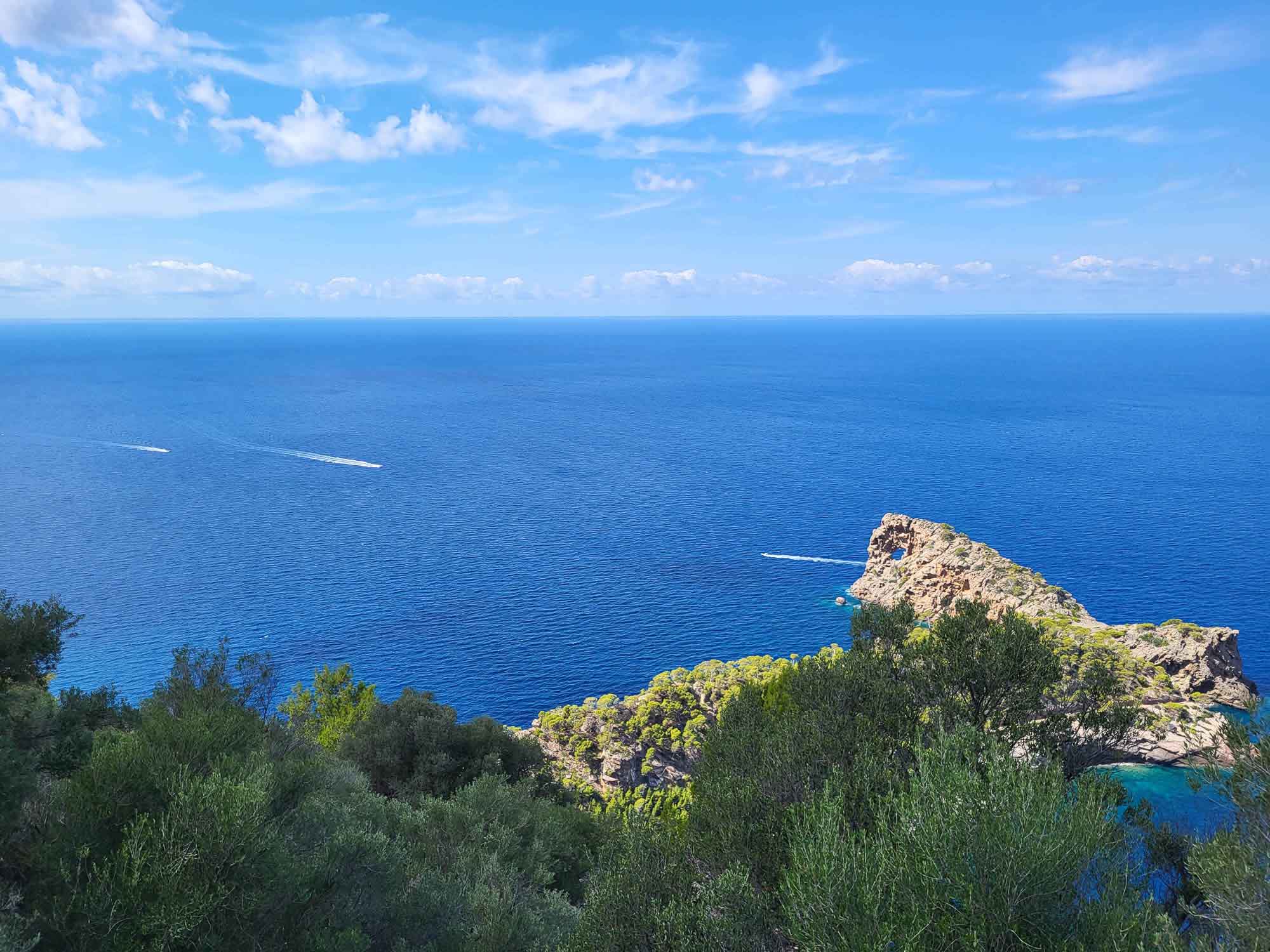Aussicht auf die Halbinsel Sa Foradada auf Mallorca mit dem tiefblauen Mittelmeer und vorbeifahrenden Booten.