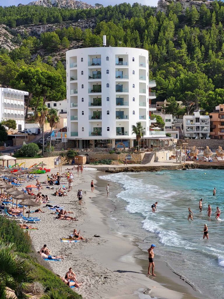 Strand von Sant Elm Mallorca mit Hotel, Sandstrand und Tramuntana-Bergen.