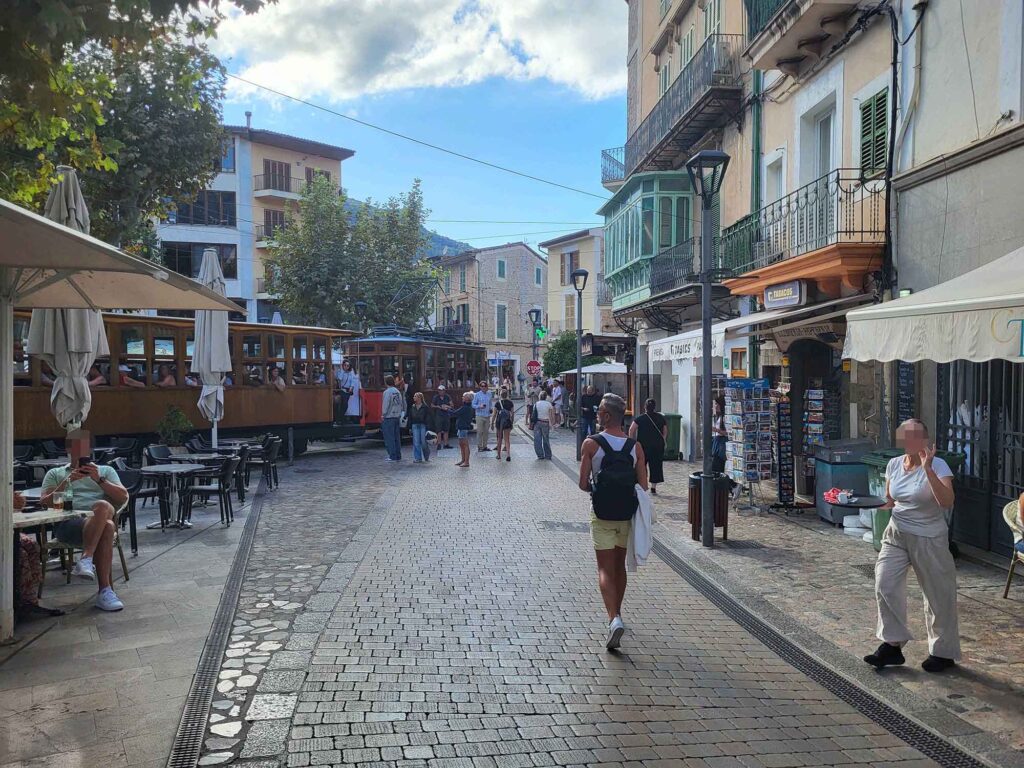 Straßenszene in Sóller auf Mallorca mit der historischen Straßenbahn, Cafés und Fußgängern in der Altstadt.