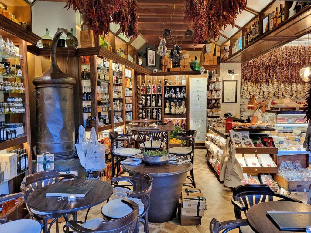 Innenansicht des Restaurants Mallorca Delicatessen in Palma de Mallorca mit rustikalem Ambiente, Feinkostregalen, Knoblauchzöpfen und Tapastischen.