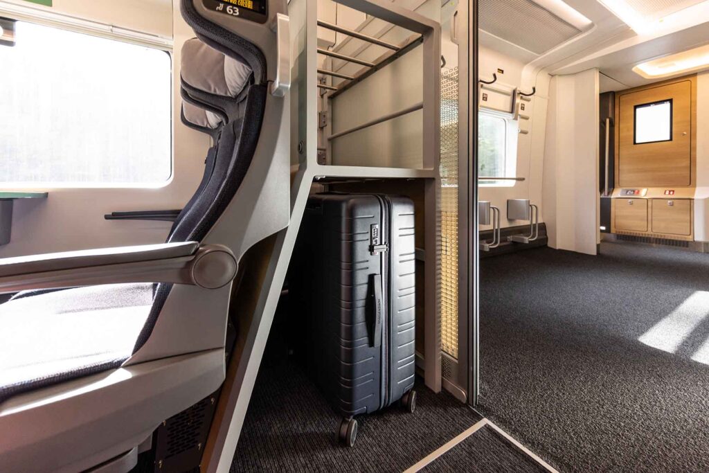 Gepäckablage im ICE L mit großem Koffer neben Sitzplätzen
