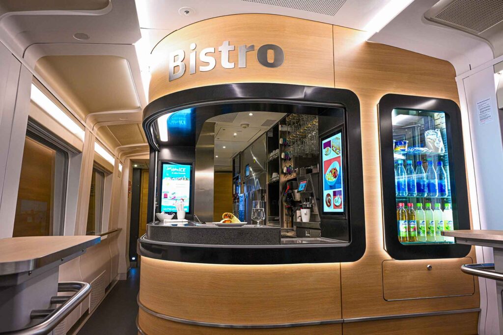 Moderne Bistro-Theke im ICE L mit Holzdesign und digitalen Displays
