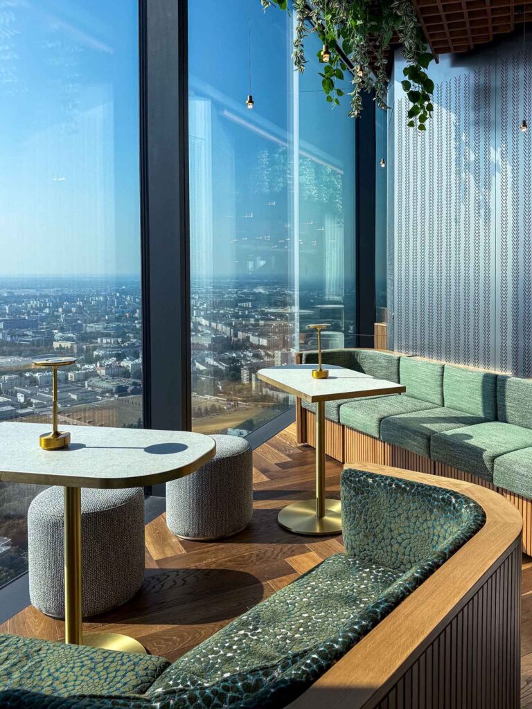 Lounge-Bereich im Highline Warsaw mit Sofas, Tischen und Panorama-Ausblick über Warschau.
