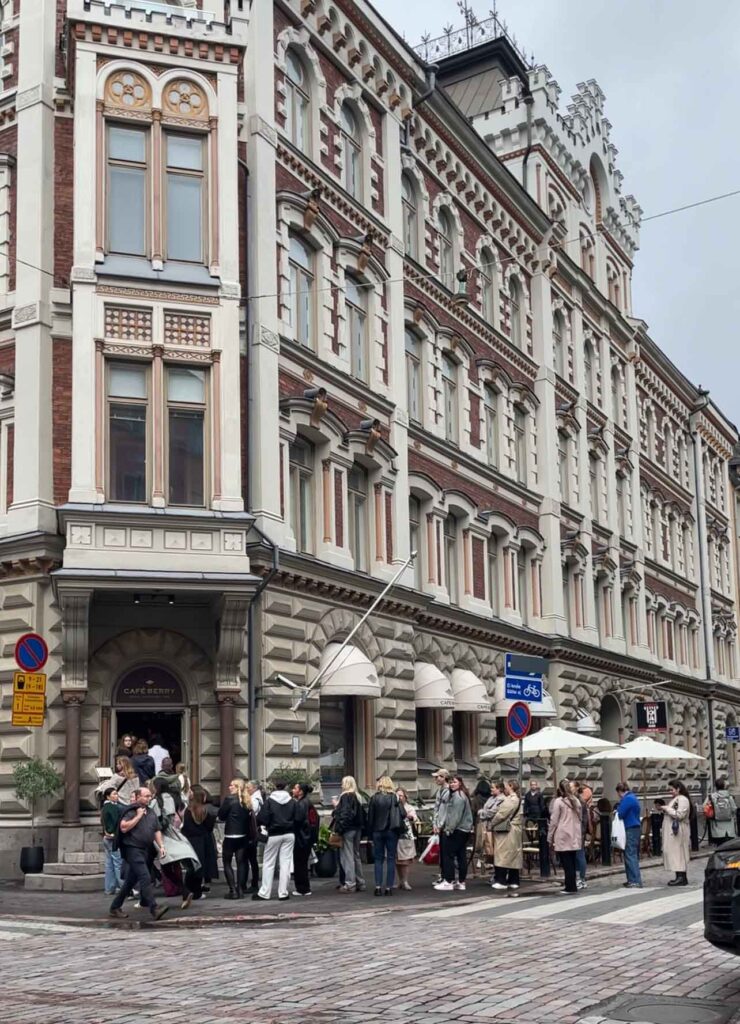 Altbau-Fassade mit Personen, die vor dem Café anstehen