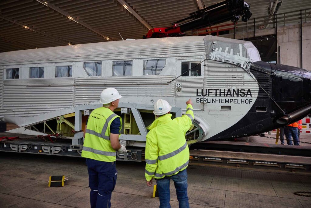 Zwei Lufthansa-Legenden vereint: Ju 52 und Lockheed Super Star in einer Ausstellung 7 Zwei Arbeiter in Schutzkleidung inspizieren den Rumpf einer restaurierten Lufthansa Junkers Ju 52 im Hangar One am Flughafen Frankfurt.