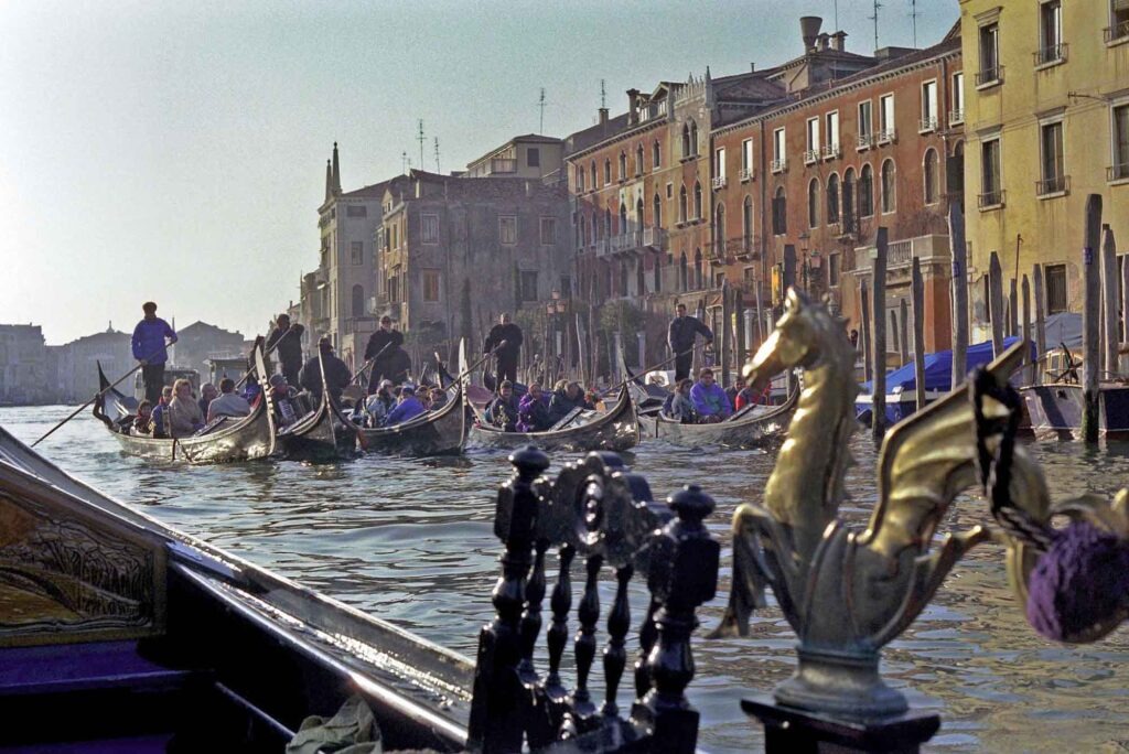 Städte vom Wasser aus entdecken: Eine neue Perspektive auf Europas Metropolen 5 Gondeln voller Touristen auf dem Canal Grande in Venedig, umgeben von historischen Palazzi und warmem Nachmittagslicht.