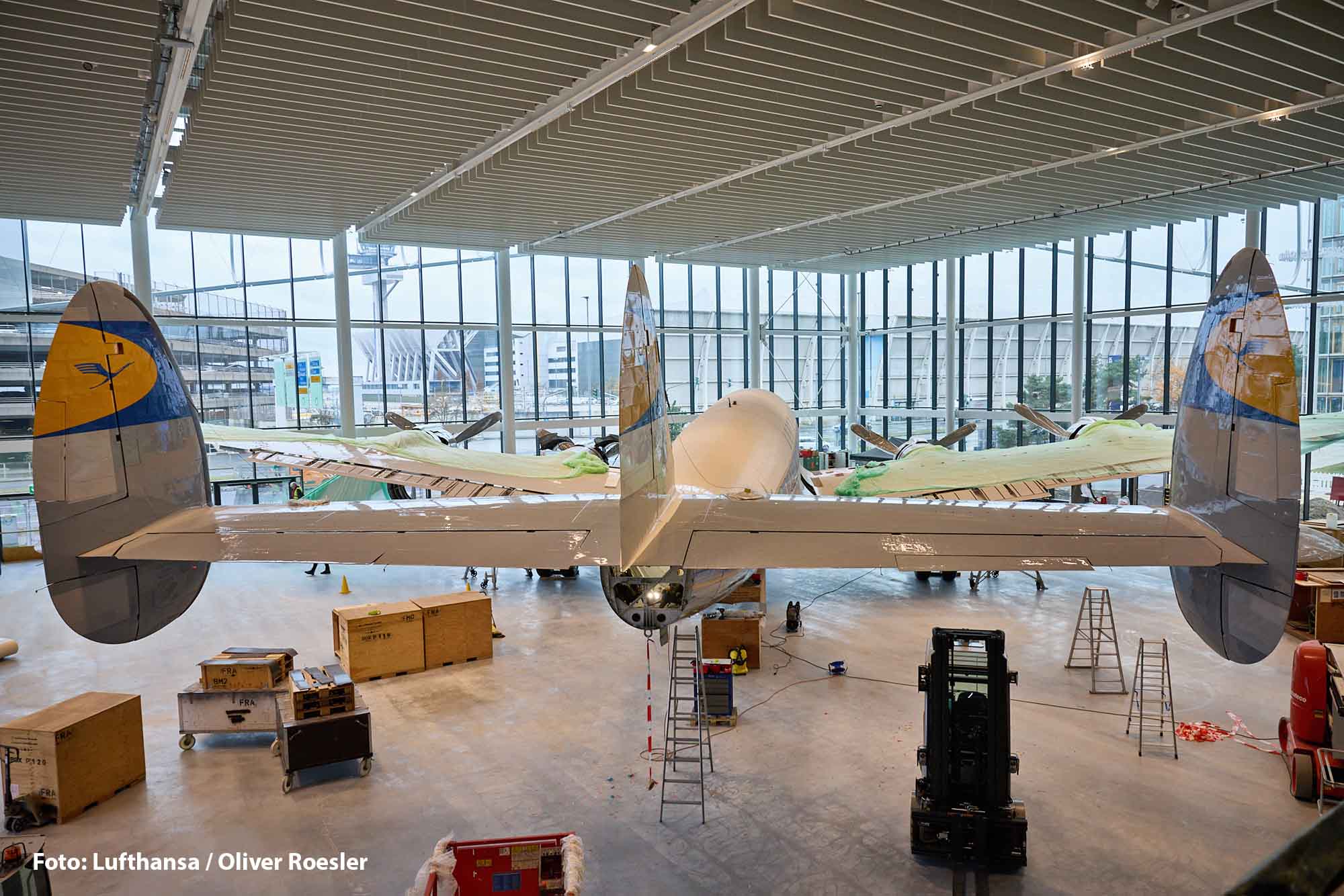 Zwei Lufthansa-Legenden vereint: Ju 52 und Lockheed Super Star in einer Ausstellung 1 Das fast vollständig montierte Heck der restaurierten Lufthansa Lockheed Super Star steht im Hangar One am Frankfurter Flughafen, umgeben von Werkzeugen, Leitern und Transportkisten während der Aufbauarbeiten.