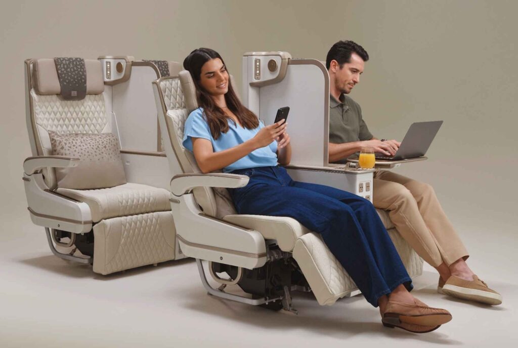 Zwei Passagiere in neuen Emirates Premium-Economy-Sitzen mit hochgefahrenen Sichtschutzwänden