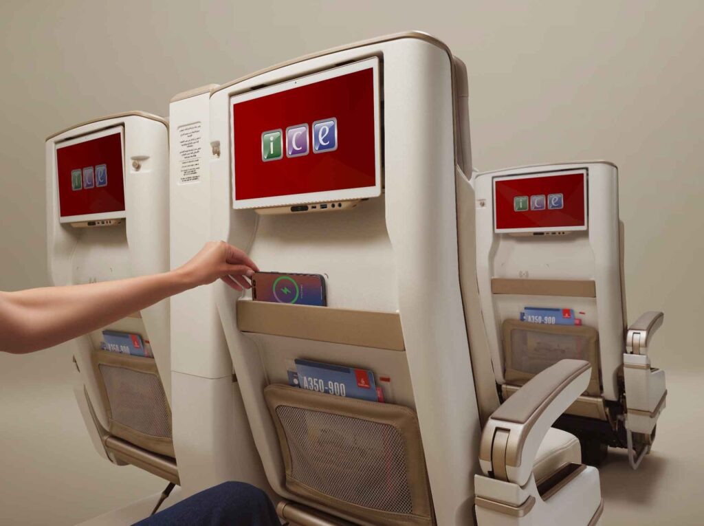 Emirates Premium-Economy-Sitz mit 4K-Bildschirm und Smartphone beim kabellosen Laden