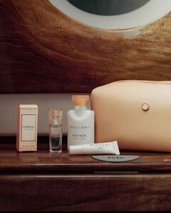 Amenity-Kits von Emirates 9 Cremefarbenes Emirates Business Class Amenity Kit für Damen mit Bulgari Omnia Crystalline, Lotion, Lippenbalsam und Kosmetiktasche auf einer Ablage im Flugzeug.
