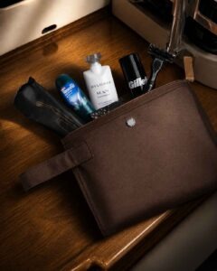 Amenity-Kits von Emirates 10 Braunes Emirates Business Class Amenity Kit für Herren mit Bulgari Man Rain Essence, Rasierer, Deodorant, Kamm und Pflegeprodukten auf einer Holzablage.