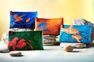 Bunte Emirates Economy Class Amenity Kits mit nachhaltigen Stofftaschen und Tierillustrationen, arrangiert auf Natursteinen als Sammelkollektion