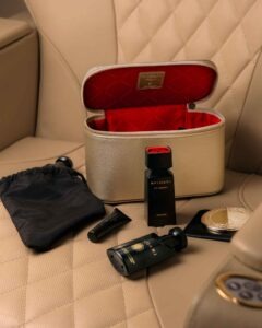 Amenity-Kits von Emirates 17 Champagnerfarbenes Emirates First Class Amenity Kit für Damen mit rotem Innenfutter, Bulgari Le Gemme Sahare, Pflegeprodukten und Spiegel auf einem First-Class-Sitz.