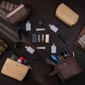 Amenity-Kits von Emirates 16 Flach arrangierte Emirates Amenity Kits für First und Business Class mit Bulgari Düften, Pflegeprodukten, Taschen, Kämmen, Rasierern und Reiseutensilien auf dunklem Untergrund.