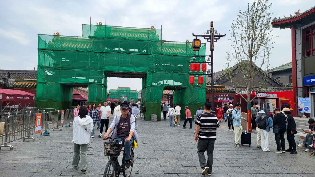 Kaiserpalast Shenyang – Die „Verbotene Stadt“ des Nordens erleben 3 Weg mit Fußgängern und einem Radfahrer. Im Hintergrund ein eingerüstetes Tor