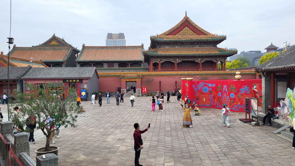 Kaiserpalast Shenyang – Die „Verbotene Stadt“ des Nordens erleben 22 Ein großer, gepflasterter Platz, umgeben von traditionellen chinesischen Palastgebäuden mit roten Mauern und Ziegeldächern. Auf dem Platz sind Besucher unterwegs, einige machen Fotos.