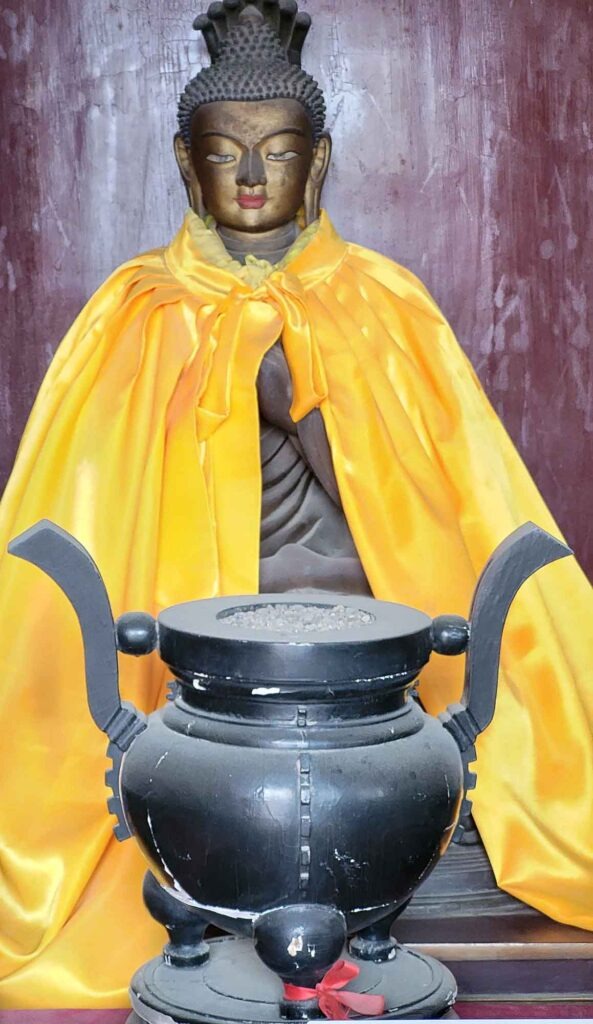 Buddha-Statue mit gelbem Tuch und traditionellem Gefäß im Putuo Zongcheng Tempel