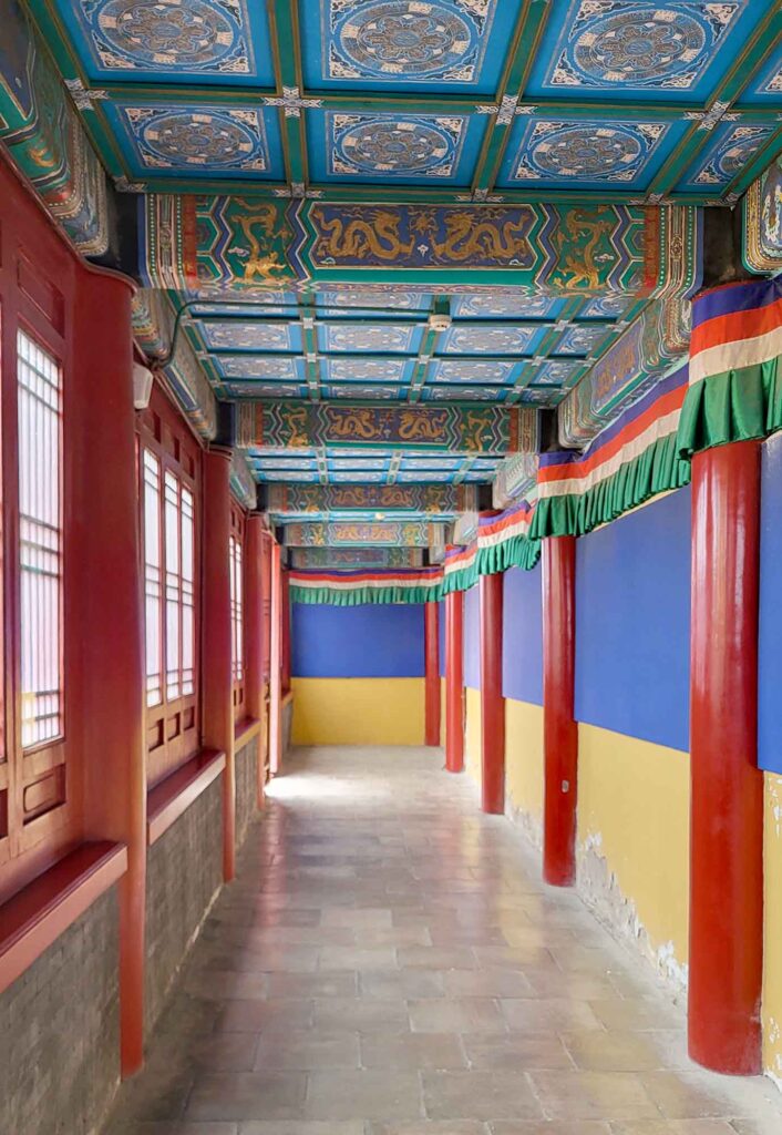 Überdachter Wandelgang mit roten Säulen im Putuo Zongcheng Tempel