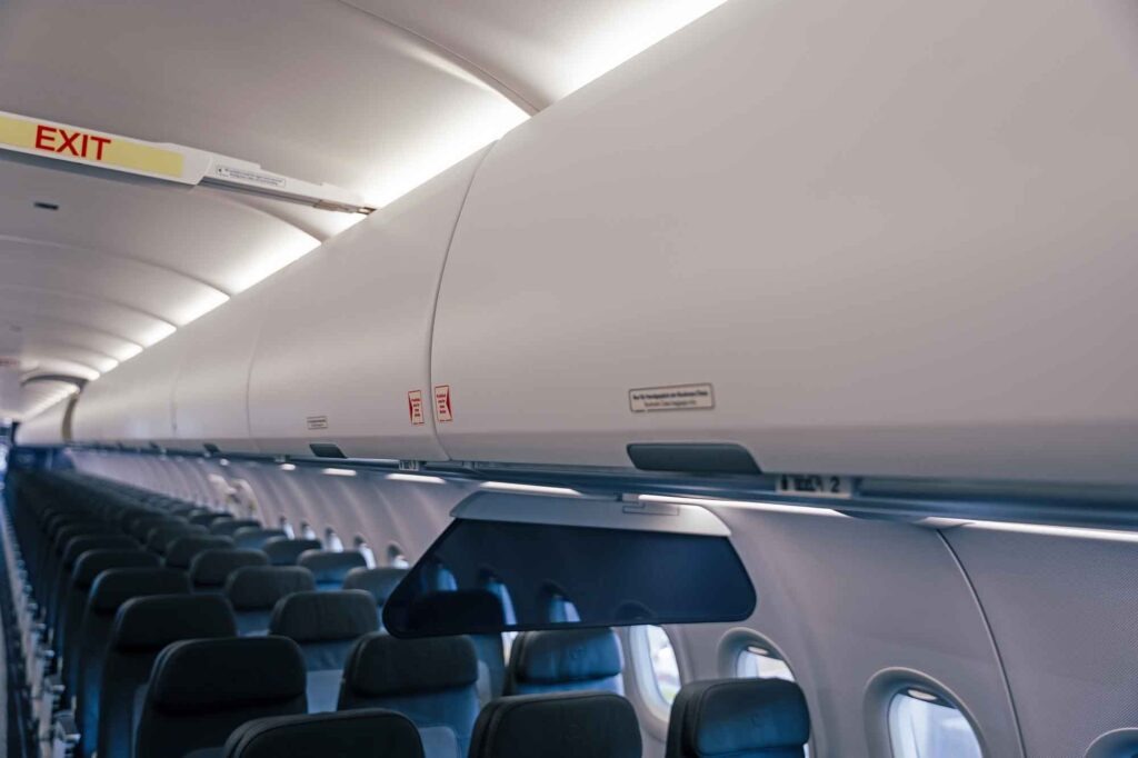Weitwinkelaufnahme der Flugzeugkabine mit Blick auf die geschlossenen, großräumigen Airspace-Gepäckfächer über den Sitzreihen. Ein beleuchtetes "Exit"-Schild ist im Vordergrund sichtbar.