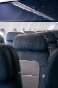 Lufthansa-Sitzplatzkonfiguration und wichtige Daten zu den „Eindeckern“ - die Fotos 5 Detailaufnahme einer ergonomischen Kopfstütze aus dunkelblauem Leder mit dem Lufthansa-Kranich-Logo. Im unscharfen Hintergrund sind die weiteren Sitzreihen der modernisierten Kabine erkennbar.