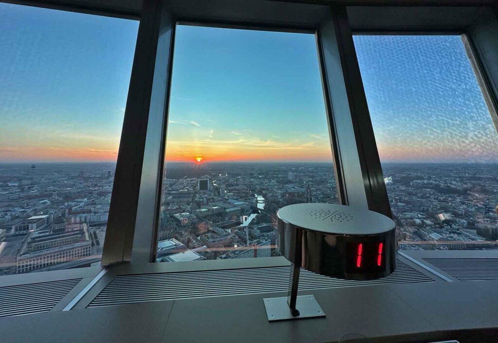 Blick aus dem Restaurant Sphere by Tim Raue im Berliner Fernsehturm auf den Sonnenuntergang über der Berliner Skyline, im Vordergrund ein Tischdisplay mit der Nummer 11.