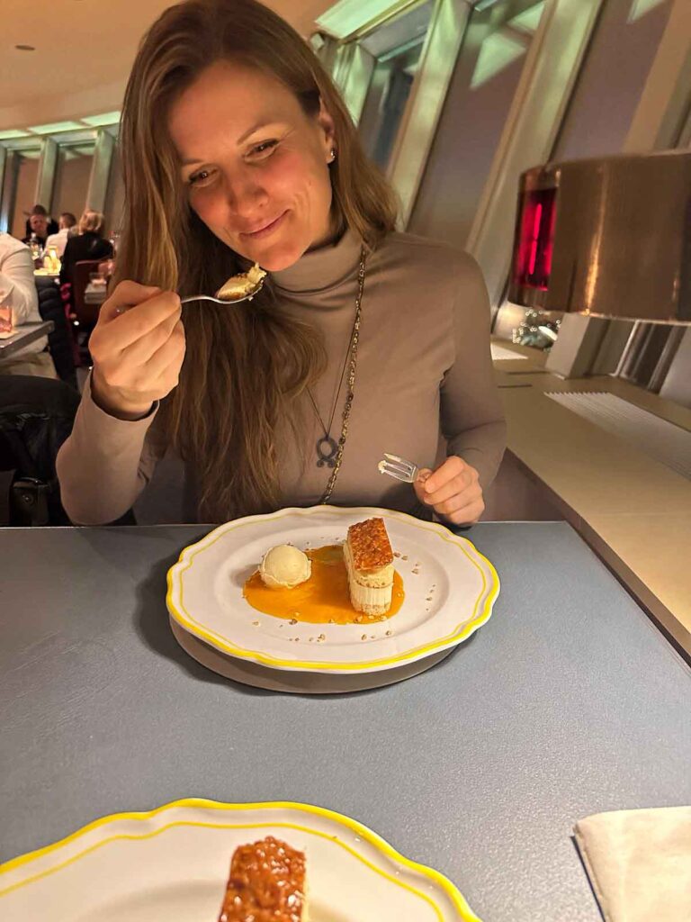 Frau probiert ein Dessert im Restaurant Sphere by Tim Raue im Berliner Fernsehturm, vor ihr ein angerichteter Dessertteller auf dem Tisch.