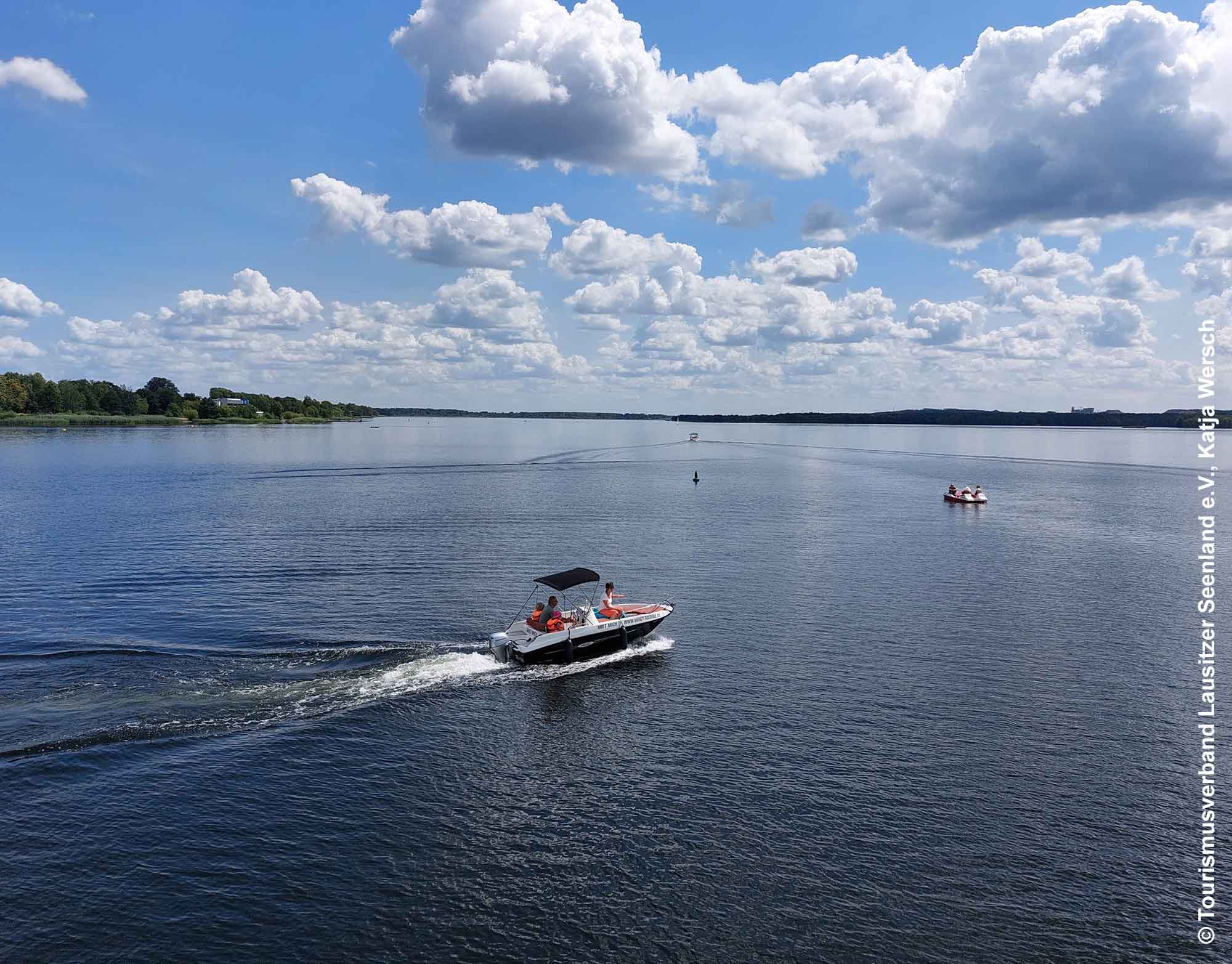 Lausitzer Seenland - Fünf-Seen-Verbund öffnet Ende Juni 1 Motorboot und Tretboot sind auf dem offenen Wasser des Senftenberger Sees unterwegs unter einem Himmel mit vielen Wolken
