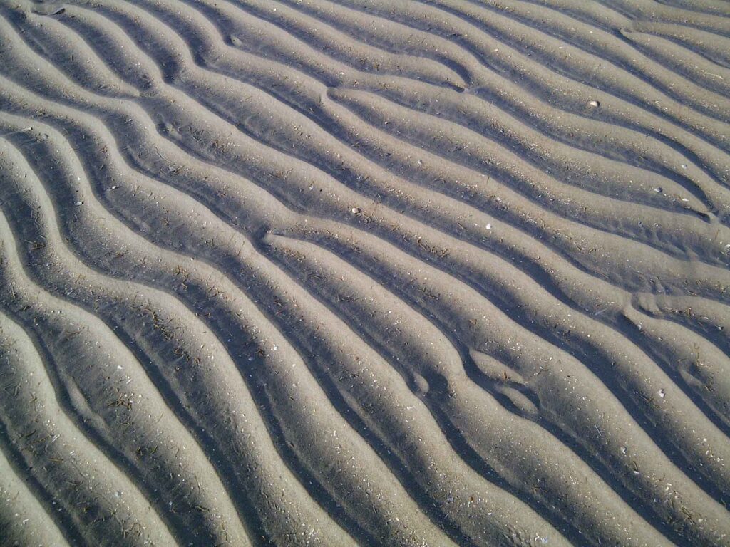 Boden des Wattenmeers mit Wellen im Sand